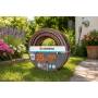 Manguera de jardín Gardena 19 mm enrollada en césped con flores, 25 m HighFLEX para riego