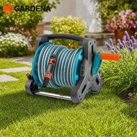 Manguera de jardín enrollada en carrete compacto con accesorios sobre césped
