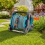 Avvolgitubo compatto con tubo da giardino e accessori su prato accanto a fiori