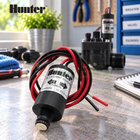 9V latching irrigation solenoid with red and black wires on workbench