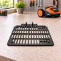 Black medium replacement plate accessory for robotic lawn mower on workbench